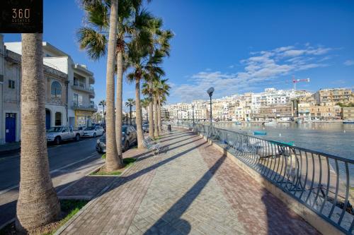a sidewalk with palm trees next to the water at Stunning 3BR w/Country View Apartment in M'Scalak by 360 Estates in Marsaskala