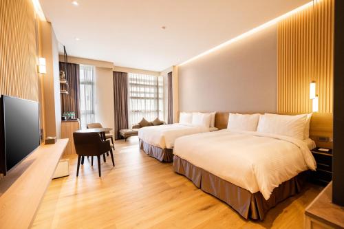 a hotel room with two beds and a flat screen tv at Euphoria Hotel Lukang in Lugang