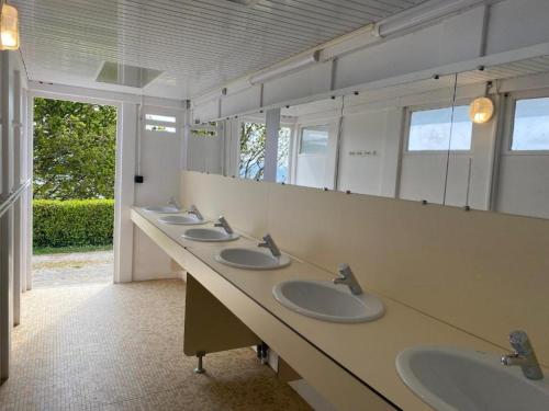Baño con una fila de lavabos y espejos en Camping Cap-Ouest en Lanvéoc