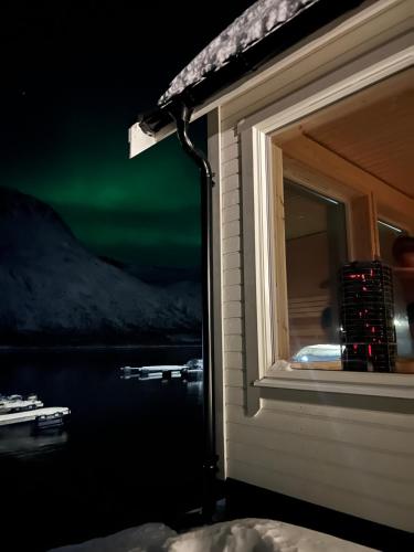 a room with a window with a view of the northern lights at Senja Fjordcamp in Torsken