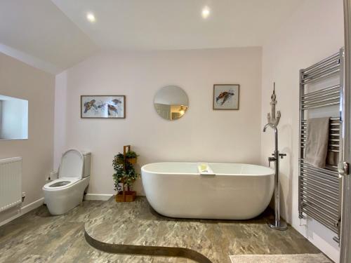 a white bathroom with a tub and a toilet at Skipper’s Cottage - Perfect for Cardiff & Penarth in Cardiff