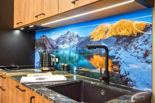 a kitchen with a mountain mural above a sink at Sienkiewiczówka in Rabka-Zdrój