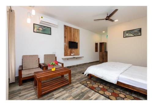 a bedroom with a bed and a chair and a tv at Grand Narmada Jungle Homestay Resort-Bandhavgarh in Tāla