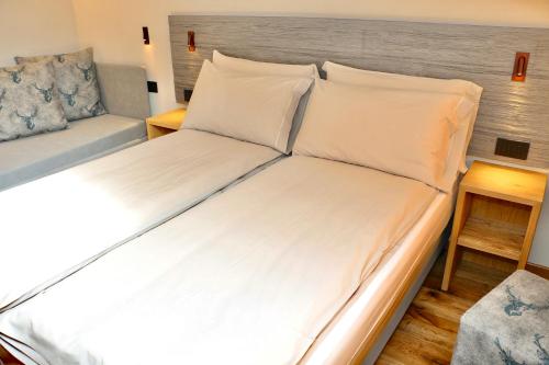 a bed with white sheets and a couch in a room at Hotel Galli's - Centro in Livigno