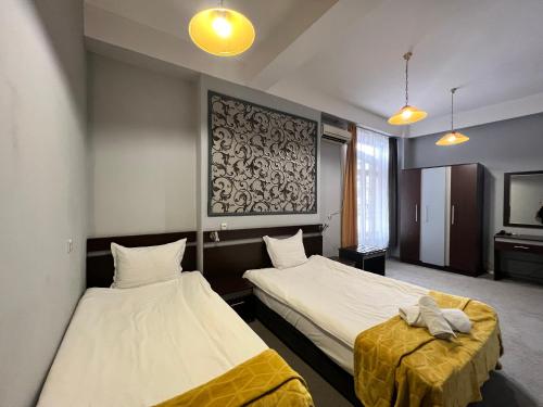 a hotel room with two beds and a tv at Family Hotel Central in Shumen