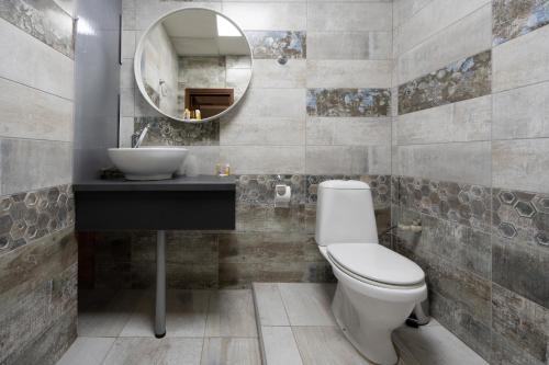 a bathroom with a toilet and a sink and a mirror at Family Hotel Central in Shumen