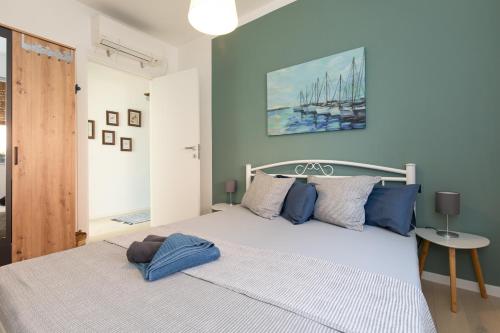 sypialnia z dużym białym łóżkiem i niebieskimi poduszkami w obiekcie Apartment Libelle 5 star apartment in Krk! w Krku
