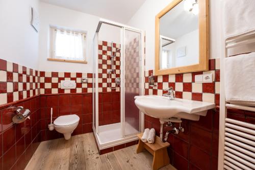 e bagno con servizi igienici, lavandino e doccia. di Hotel Obereggen a Obereggen