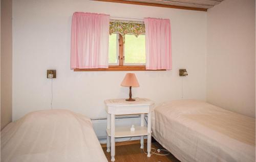 a bedroom with two beds and a window with pink curtains at Awesome Home In Bredaryd With Kitchen in Bredaryd