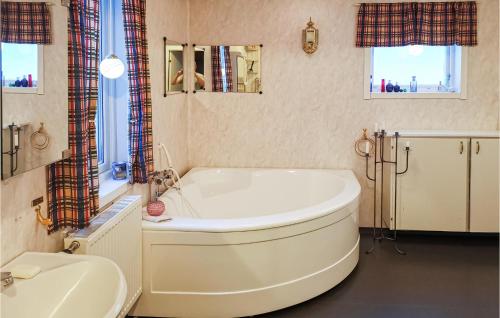 uma grande banheira branca numa casa de banho com lavatório em Beautiful Home In Karlsviken With Kitchen 