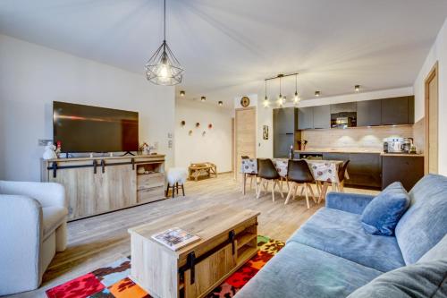 un salon avec un canapé bleu et une cuisine dans l'établissement Echo du Pleney A107, à Morzine