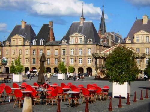 eine Gruppe von Tischen und Stühlen vor einem Gebäude in der Unterkunft Maison de 2 chambres avec terrasse a Deville in Deville