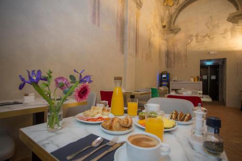 a table with breakfast foods and orange juice and flowers at Casual Rinascimento Firenze in Florence
