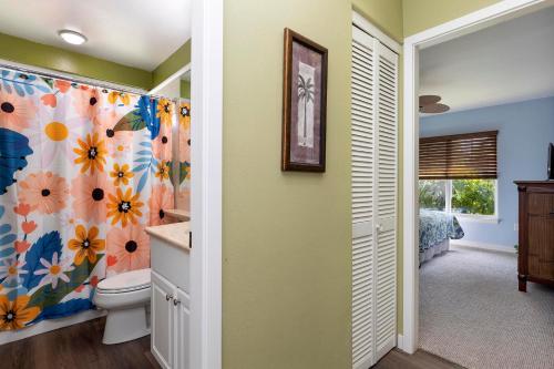 a bathroom with a toilet and a flower shower curtain at Newly Updated Condo At Waikoloa Colony Villas in Waikoloa