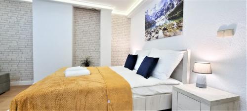 a white bedroom with a bed with a yellow blanket at VIP Apartamenty Tetmajera Centrum in Zakopane