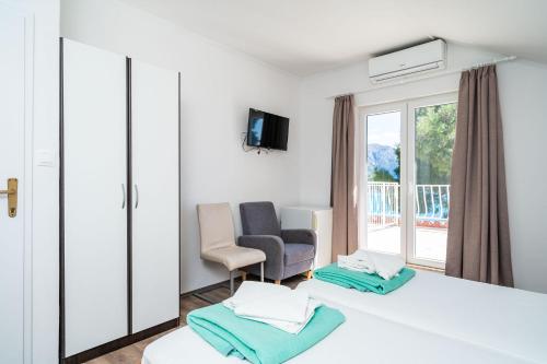 a room with two beds and a chair and a window at Guest House Daniela in Mlini
