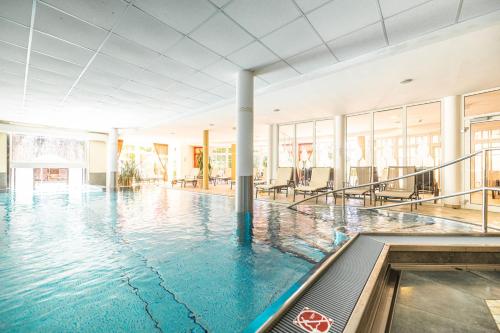 a swimming pool with blue water in a building at Landhotel Schermer in Westendorf