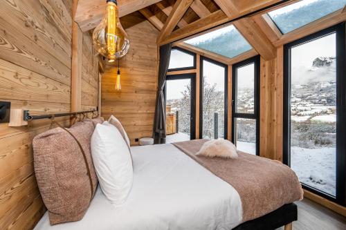 ein Schlafzimmer mit einem Bett in einem Zimmer mit Fenstern in der Unterkunft Les chalets d'Éléna in Saint-Jean-Saint-Nicolas