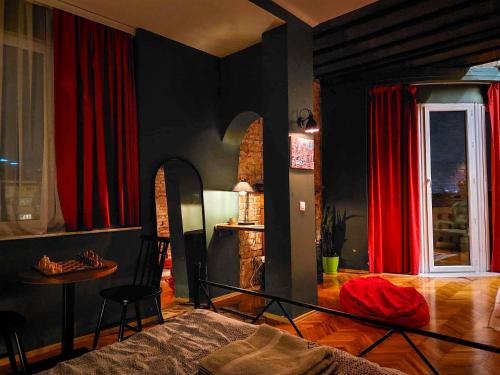 a bedroom with red curtains and a table and a bed at Prishtina Center Hostel in Pristina