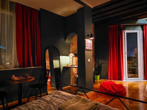 a bedroom with red curtains and a table and a bed at Prishtina Center Hostel in Prishtinë