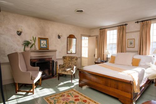 1 dormitorio con 1 cama, chimenea y silla en The Old Inn On The Green, en New Marlborough