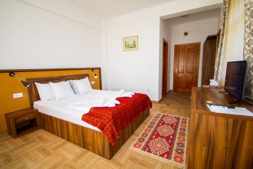 a bedroom with a bed with a red blanket and a television at Mai Danube in Eşelniţa