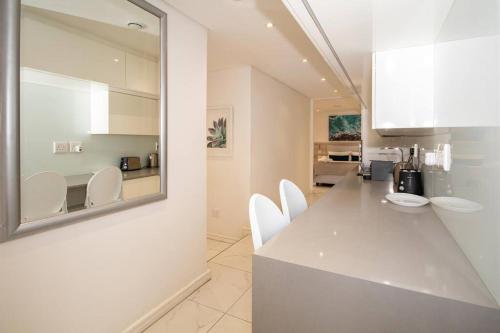 a white kitchen with white chairs and a counter at Magnificent apartment 506 The Granger in Cape Town