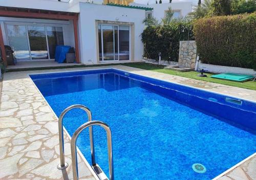 a swimming pool with blue water in front of a house at Villa Poseidon in Perivolia