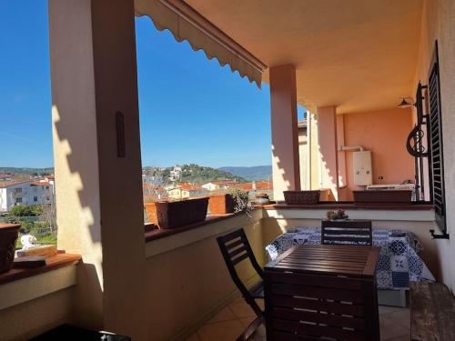 d'un balcon avec une table, des chaises et une grande fenêtre. dans l'établissement Sardegna: mare e montagna IUN R0346, à Oliena