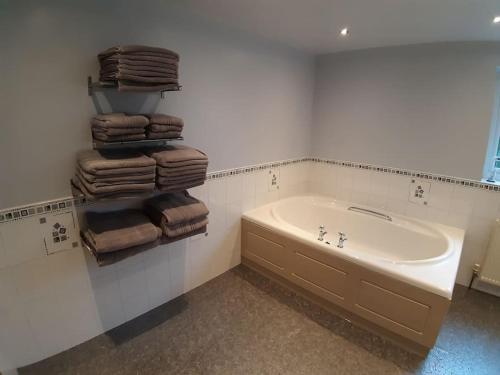 ein Badezimmer mit einer Badewanne und einem Haufen Handtücher in der Unterkunft Countryside Home Snowdon & Snowdonia National Park in Llanrug