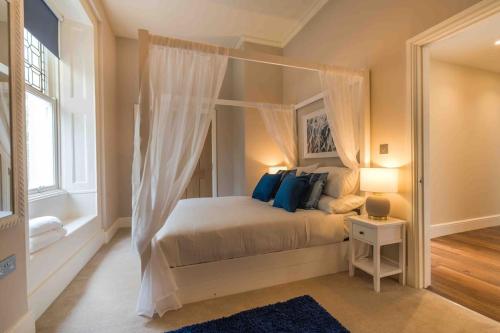 a bedroom with a canopy bed with blue pillows at Beautiful Beach side Apartment in Torquay