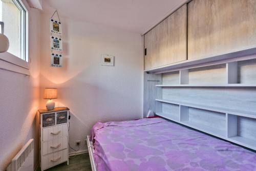 Un pequeño dormitorio con una cama morada y una ventana en Bord de mer, a 250 m de la plage a Lacanau, en Lacanau