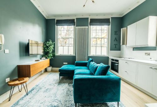 a living room with a blue couch and a table at Abbey Hideout - Lovely 1-Bed APT in Heart of Bath in Bath