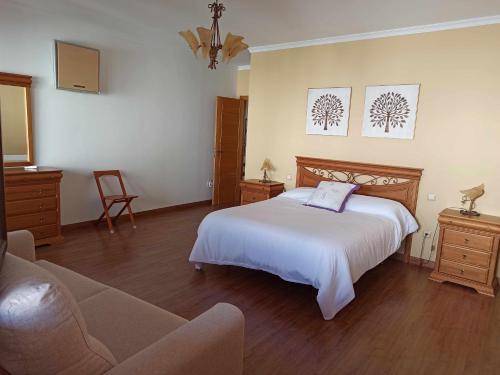 1 dormitorio con cama blanca y sofá en El Almez 2 Casa rural, 