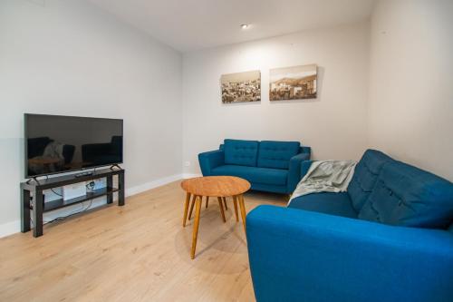 a living room with two blue couches and a table at Apartamento junto al ayuntamiento de Santander in Santander