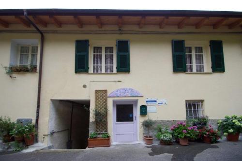 a white house with green shuttered windows and a door at Agriturismo Nonnamelia in Nasino
