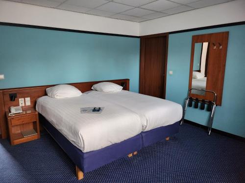 a bedroom with a large bed with a blue wall at Hotel Royal Zelzate in Zelzate