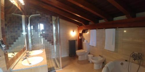 a bathroom with two sinks and a shower and two toilets at Posada El Pozo in Castanedo