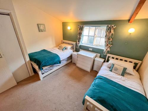 a small room with two beds and a window at Blueberry Cottage in Bedfield