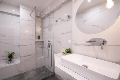 a white bathroom with a sink and a shower at Plaka With Acropolis Rooftop View Access in Athens