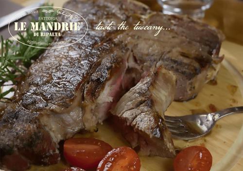 ein Steak auf einem Teller mit Tomaten und einer Gabel in der Unterkunft Le Mandrie di Ripalta in Montespertoli