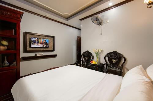 a bedroom with a bed and two chairs and a fan at Nam Hai Hotel in Hanoi