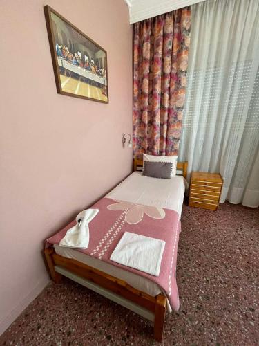 a small bedroom with a bed with a pink blanket at Hotel Angela in Asprovalta