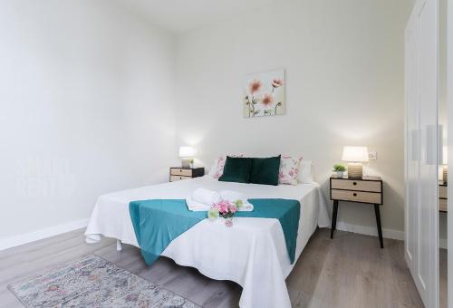 ein weißes Schlafzimmer mit einem Bett und einem Tisch mit Blumen darauf in der Unterkunft La Fuente de la Casona in Jerez de la Frontera