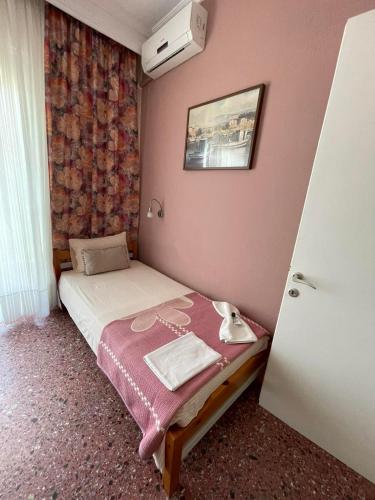 a small bedroom with a bed with pink walls at Hotel Angela in Asprovalta