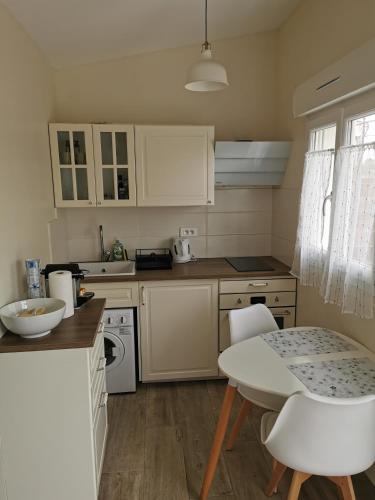 une cuisine avec des armoires blanches et une table et des chaises dans l'établissement Studio indépendant à 2 minutes du golf du Luberon, à Pierrevert