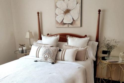 um quarto com uma cama grande com lençóis brancos e almofadas em Haz de mi Rincón en Mugardos tu experiencia. em Mugardos