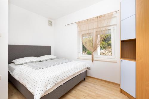 une chambre blanche avec un lit et une fenêtre dans l'établissement Apartman Ponte Mohito, à Punat