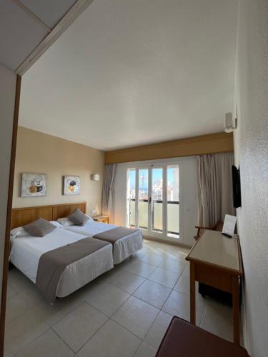 ein großes Schlafzimmer mit einem großen Bett und einem Schreibtisch in der Unterkunft Hotel Albatros in Gandía