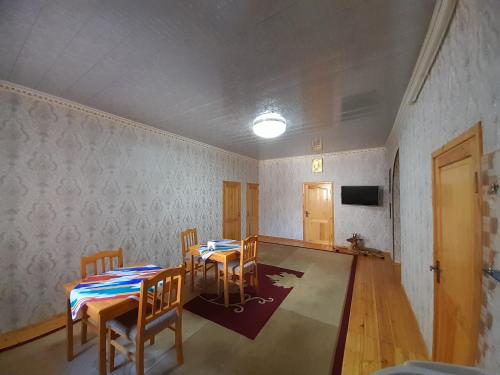 a room with two tables and chairs and a tv at KHIVA ABDULLA Guest House in Khiva